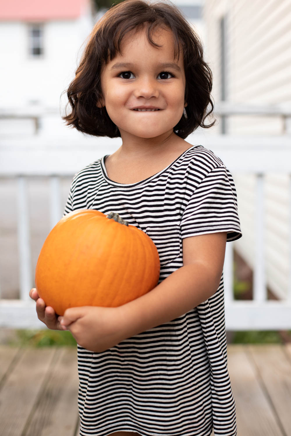 toddler with french bob holding a pumpkin